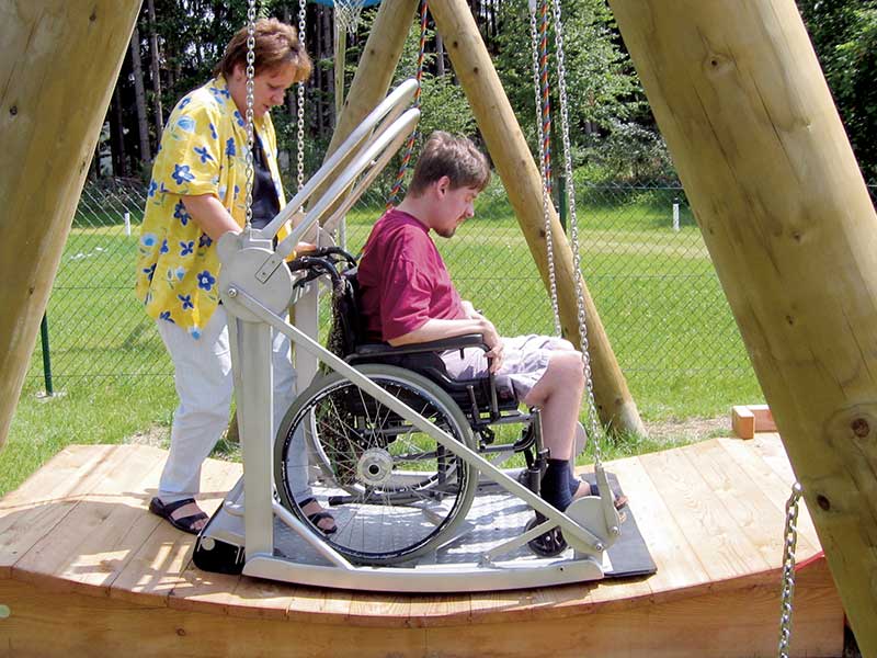 Bild einer Schaukel für Rollstuhlfahrer. Ein Rollstuhlfahrer befindet sich im inneren