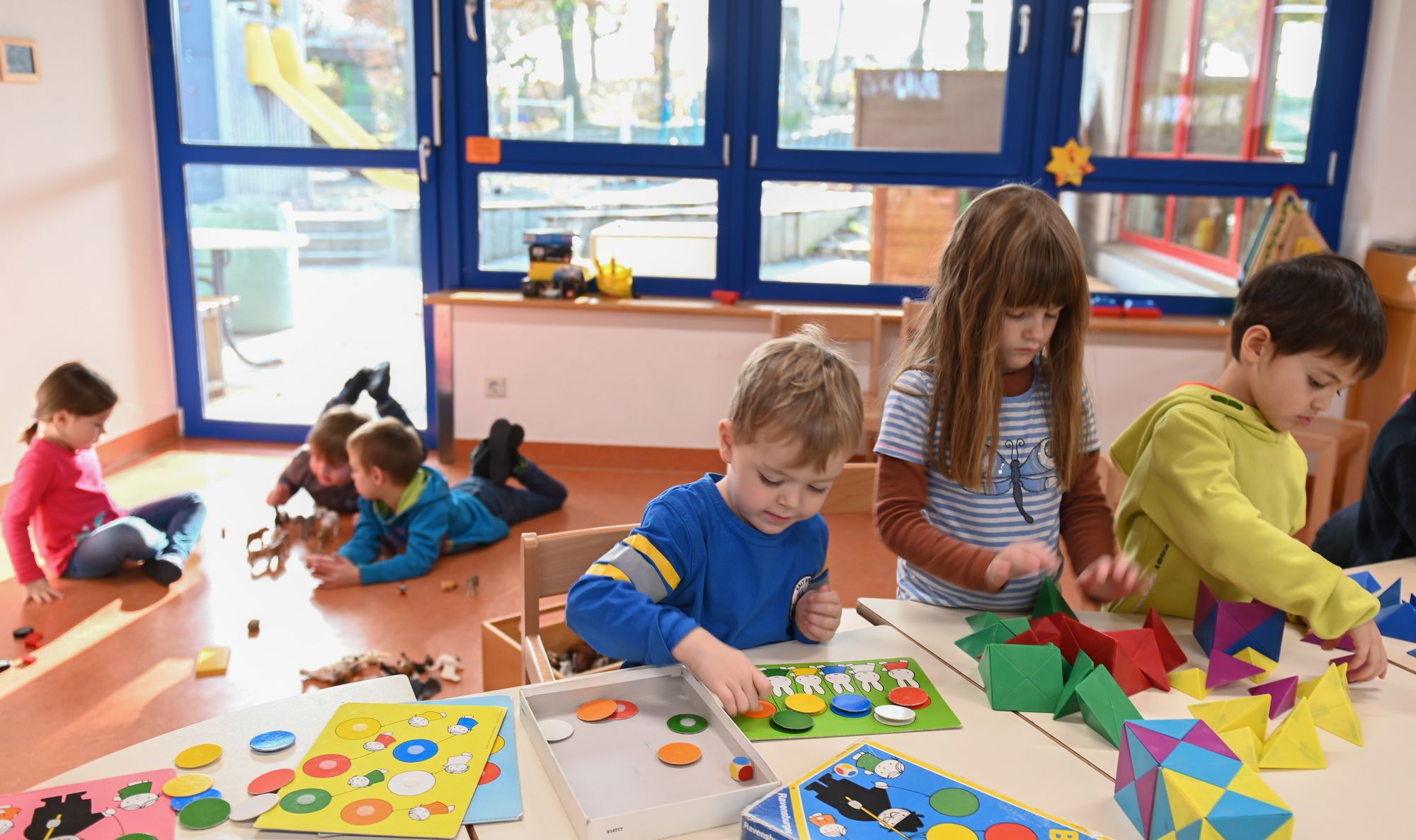 Mehrere Kinder die im Gebäude einzeln Geschicklichkeitsspiele spielen oder basteln.