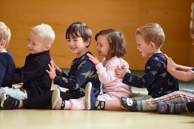 Mehrere Kinder, die Spaß haben, in einem Sitzkreis hintereinander